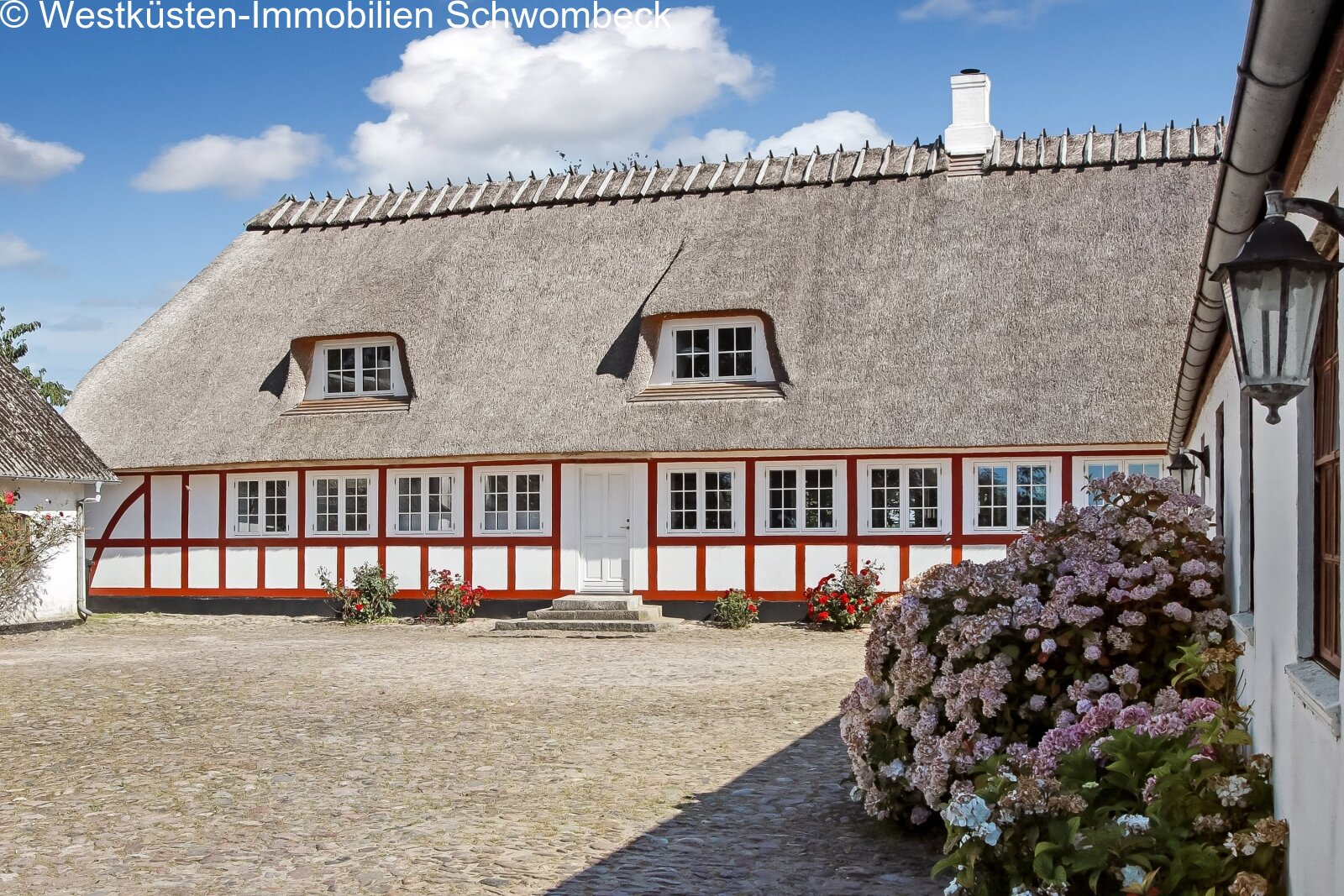 Authentisches Fachwerkhaus mit charaktervollem Reetdach und großflächigen Fensterfront