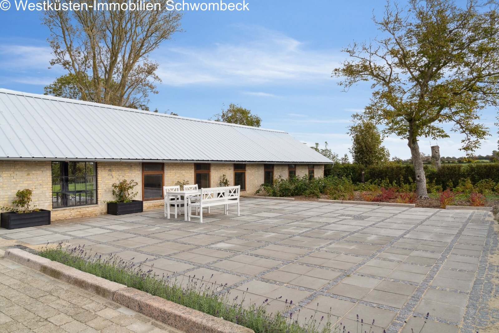 Weitläufige Terrasse mit hochwertiger Natursteinbelägen und freier Landschaftsaussicht