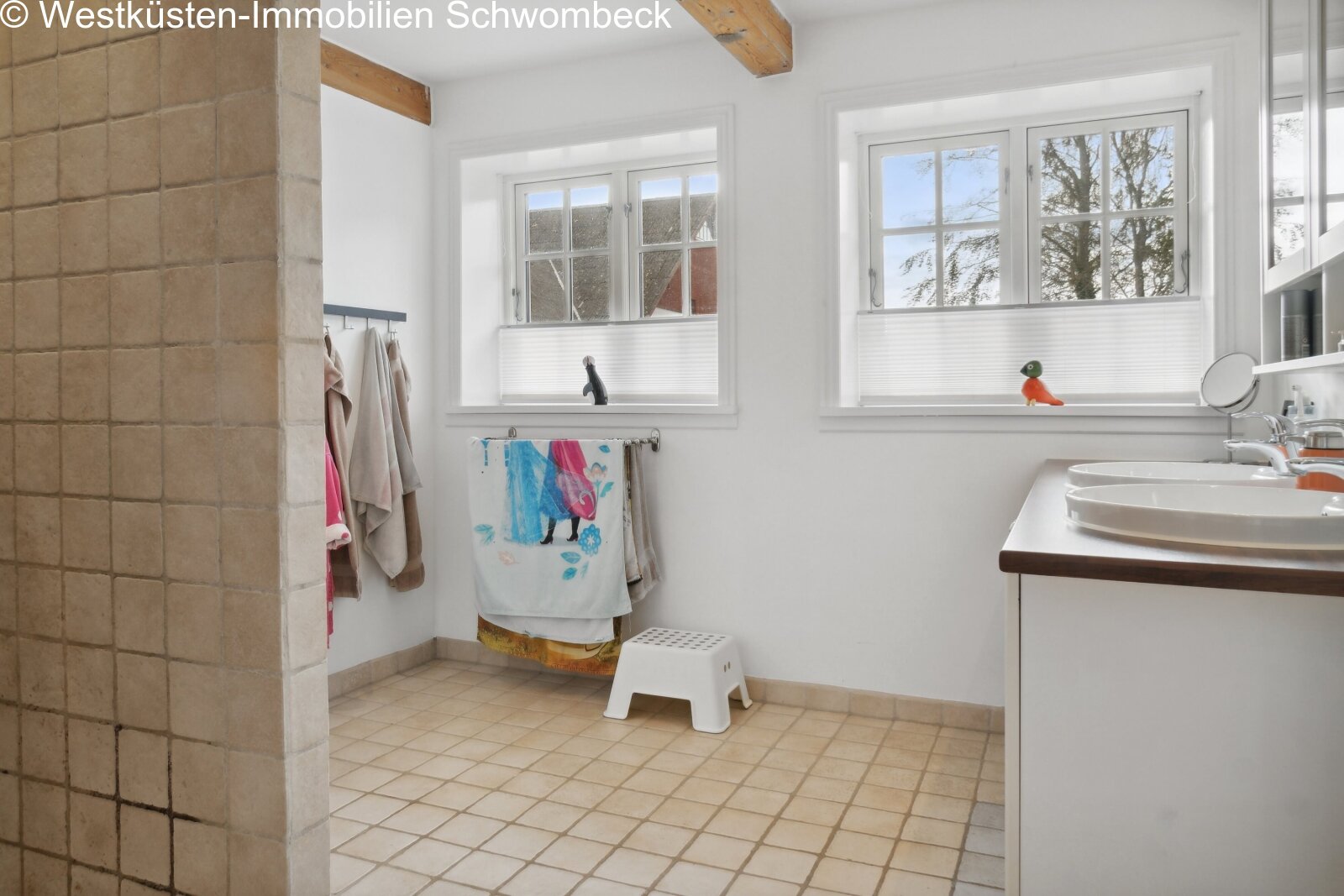 Helles Badezimmer mit großflächigen Fenstern und praktischer Doppelwaschanlage