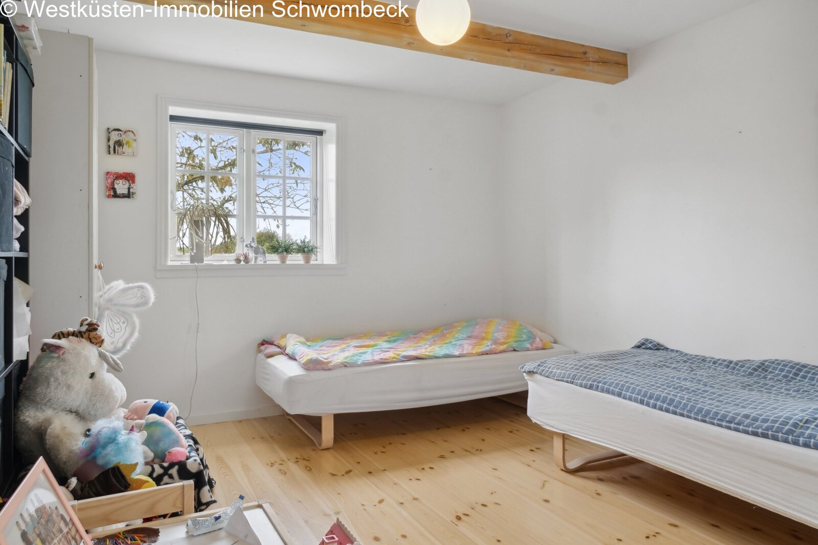 Helles Kinderzimmer mit großflächigem Fenster und Holzbalkendecke