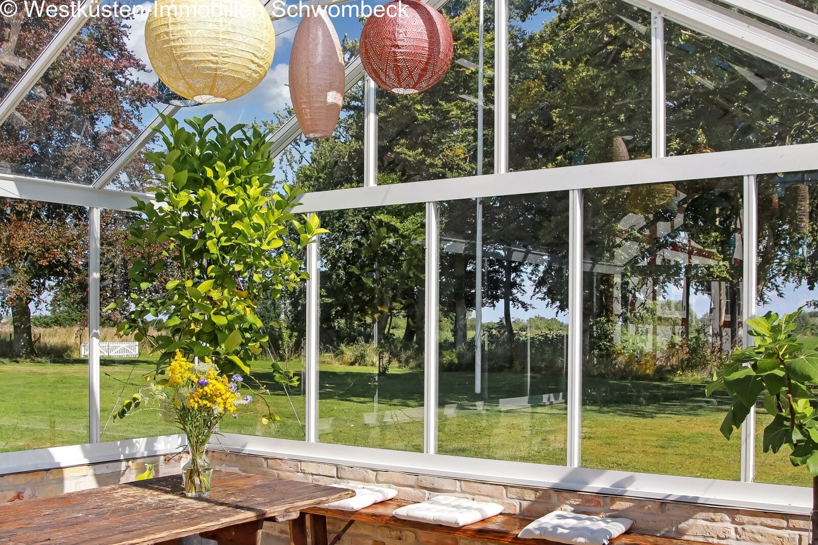 Lichterflutete Wintergarten-Lounge mit rahmenloser Glasfront und Landschaftsblick
