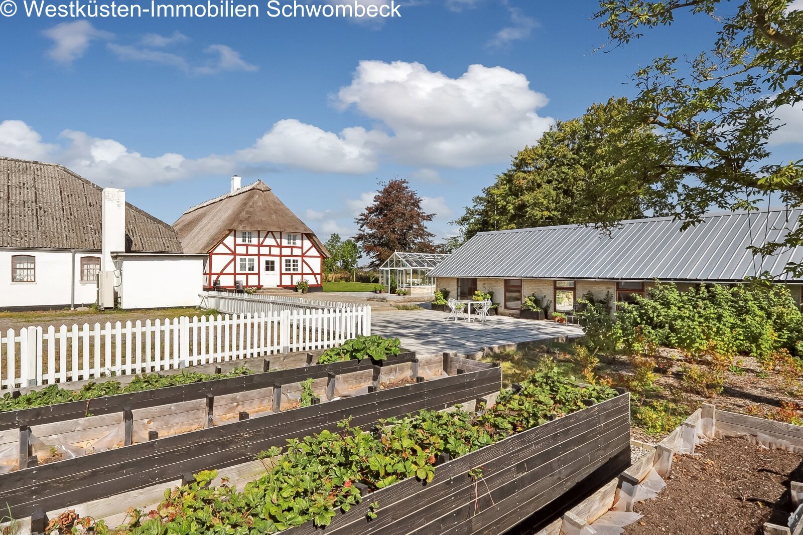 Idyllischer Außenbereich mit Hochbeeten, Gewächshaus und weitläufiger Gartenanlage