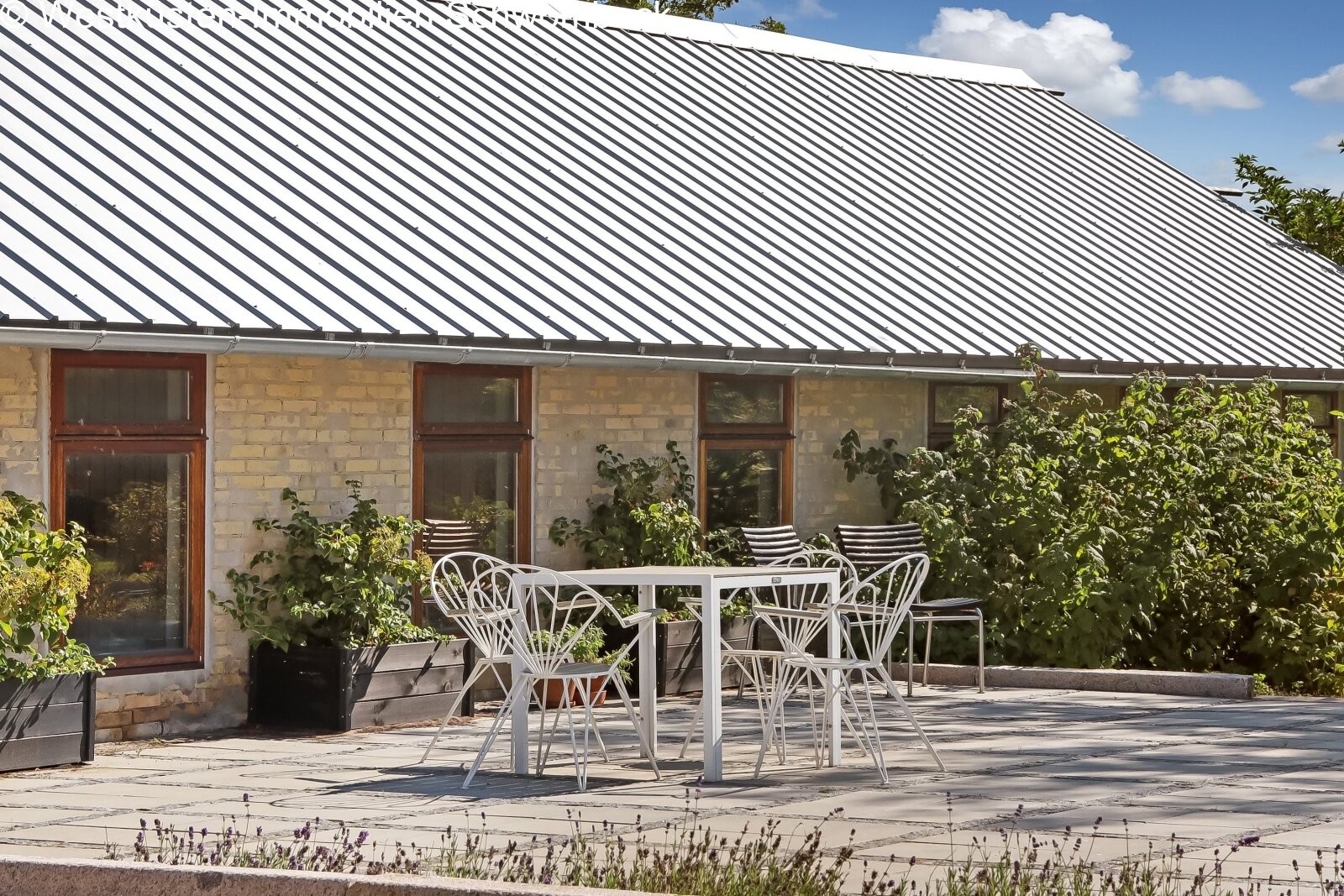 Moderne Terrasse mit Natursteinbelag und großflächiger Glasfront