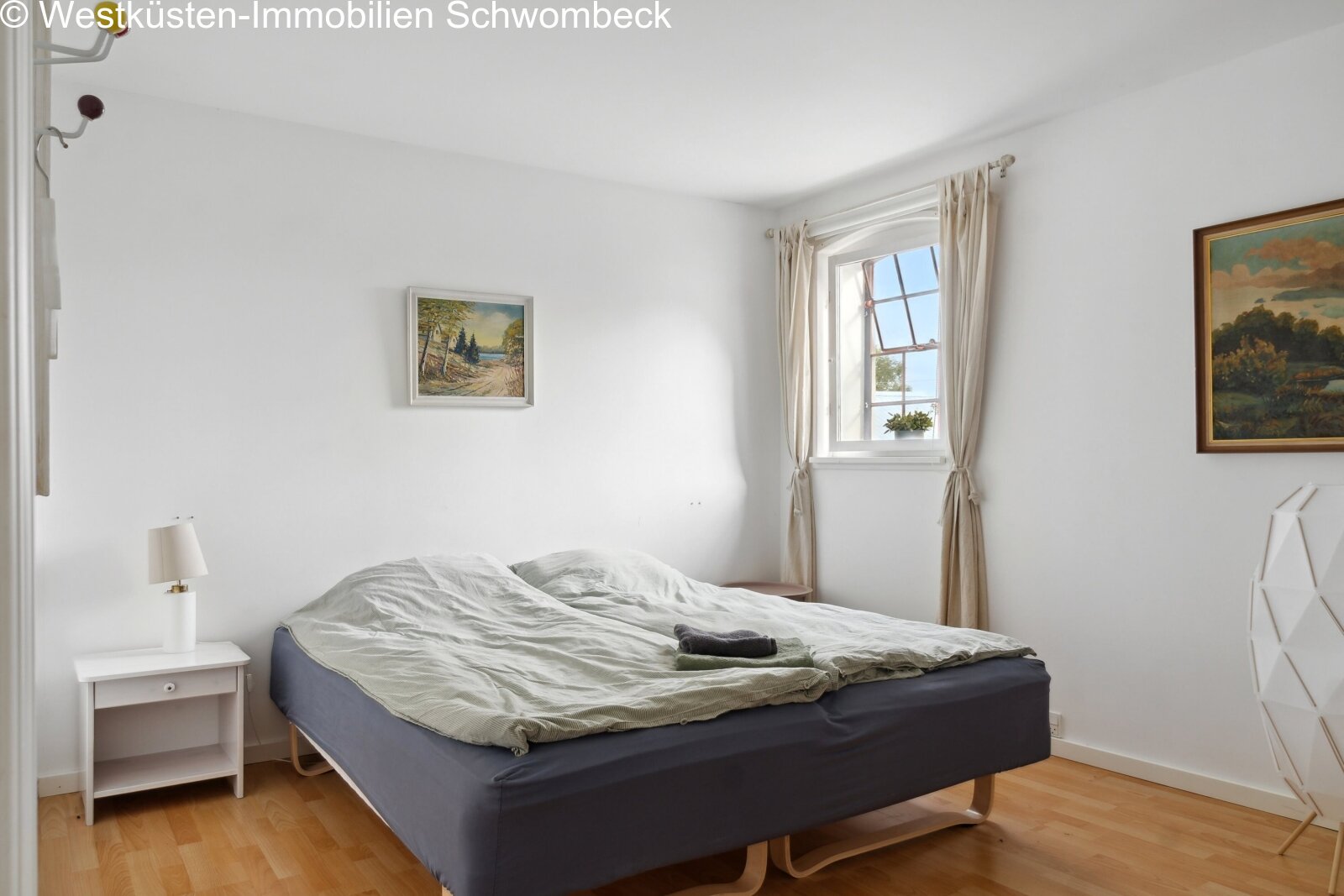 Helles Schlafzimmer mit großflächigem Fenster und Holzbalkendecke