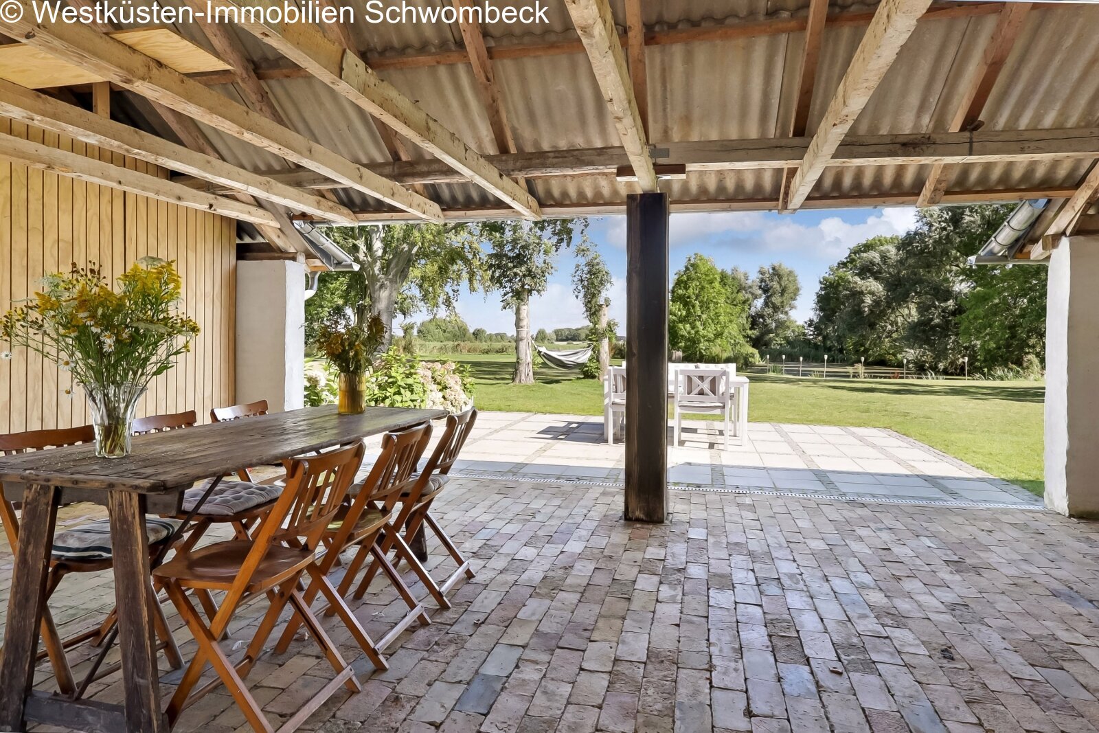 Überdachte Außenlounge mit Natursteinbelag und freiem Landschaftsblick