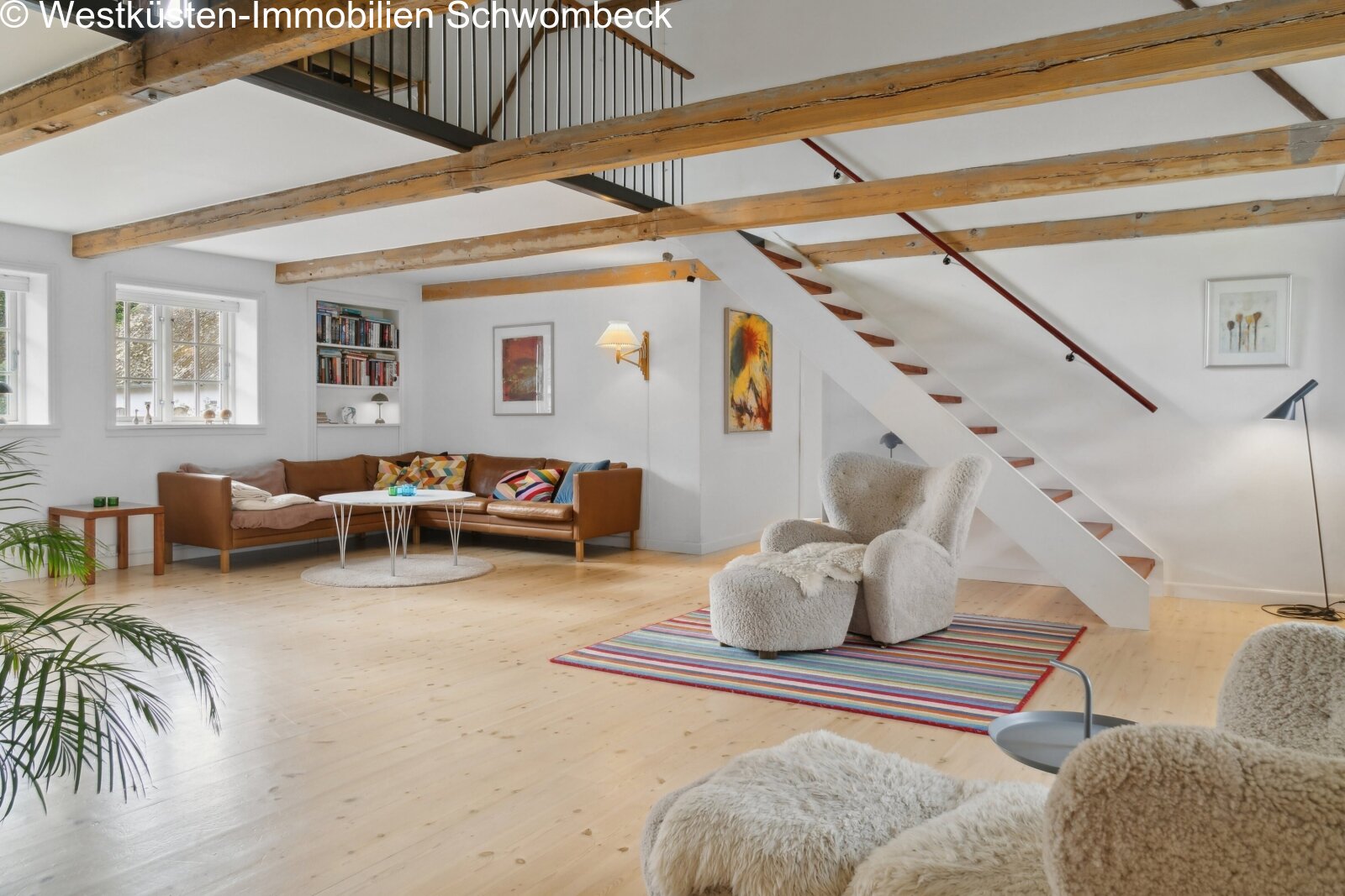 Loft-Wohnbereich mit freitragender Treppe und rustikalen Deckenbalken