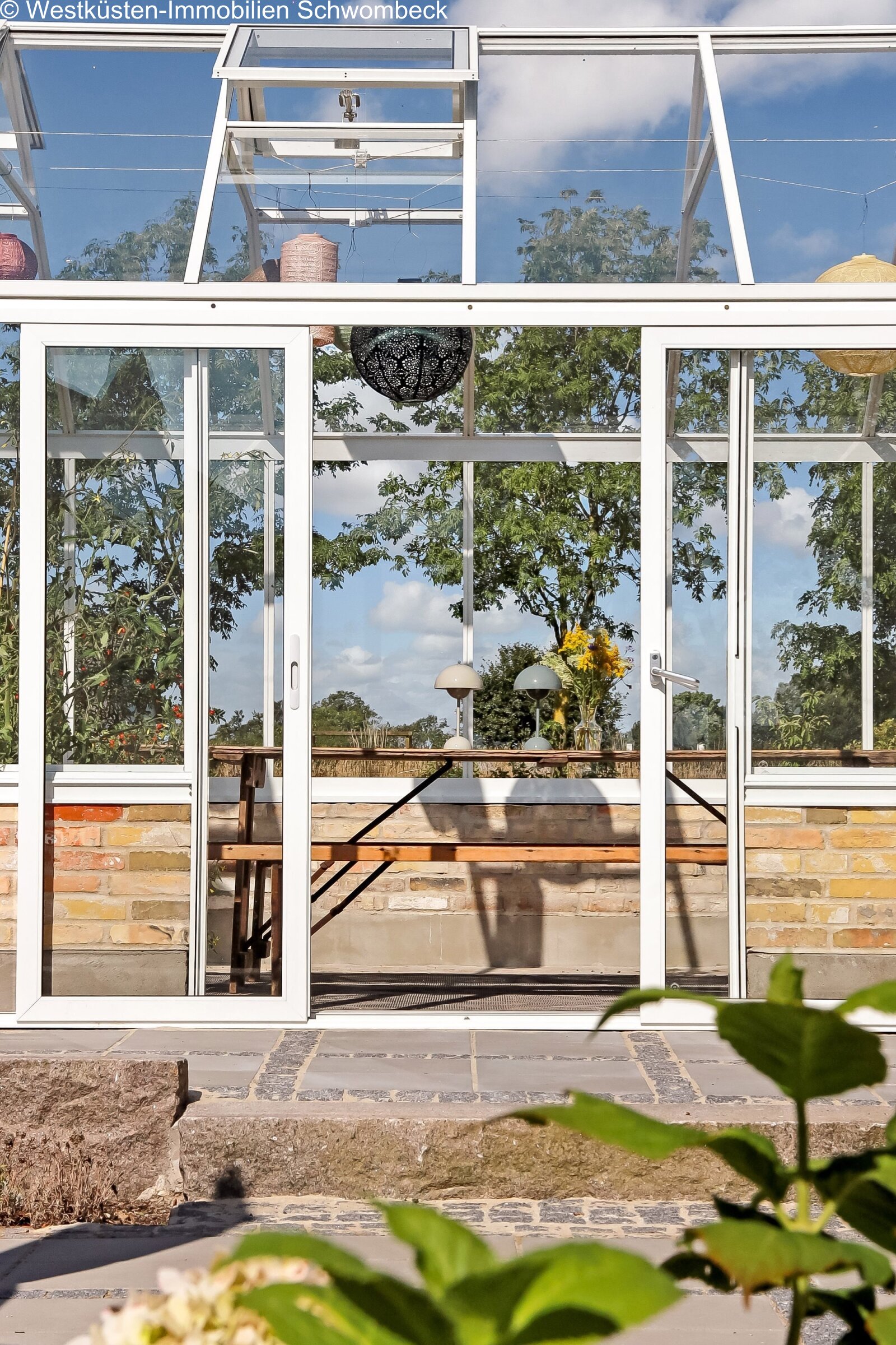 Lichterflutete Wintergarten-Lounge mit rahmenloser Glasfront und freiem Landschaftsblick