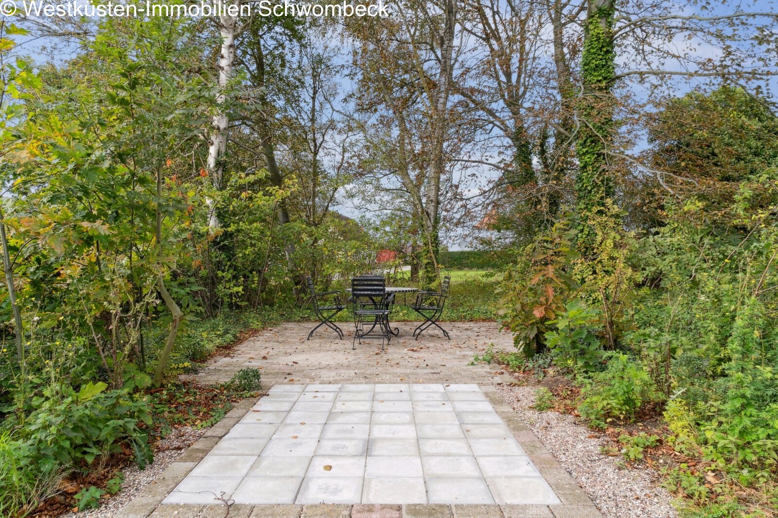 Idyllischer Gartenweg mit gepflastertem Belag und altem Baumbestand