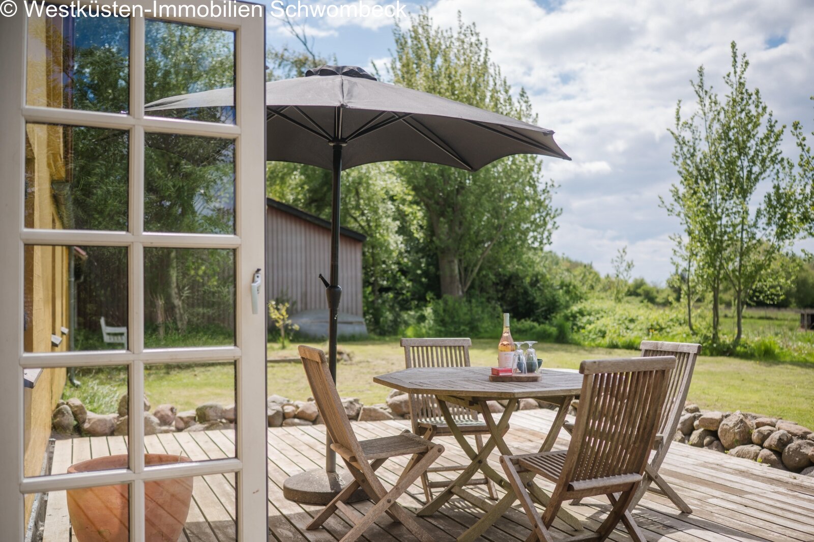 Sonnige Holzterrasse mit direktem Gartenblick und Freisitzbereich