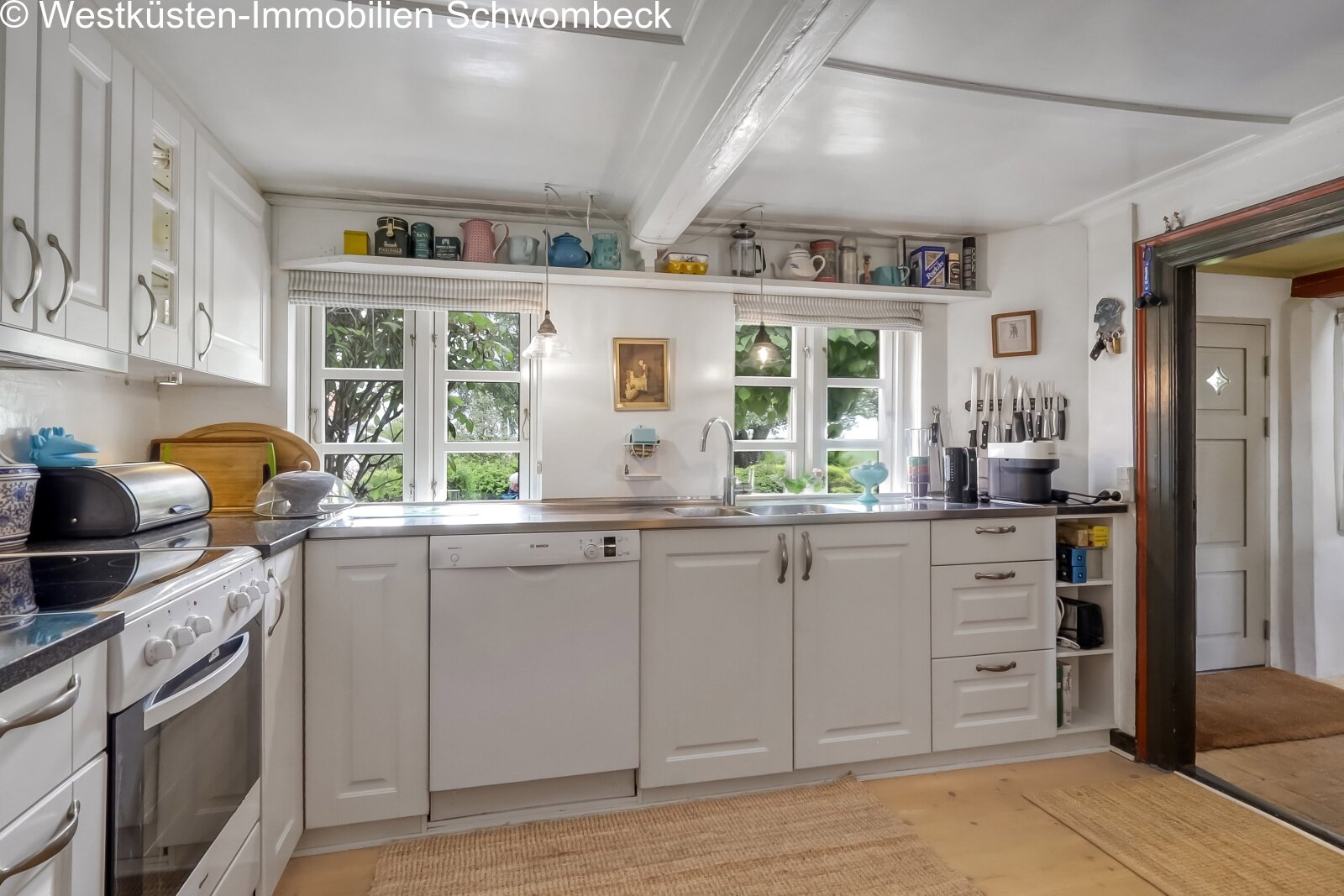 Helle Küche mit umlaufender Arbeitsfläche und großzügigen Fensterfronten zum Garten Helle Küche mit umlaufender Arbeitsfläche und großzügigen Fensterfronten zum Garten