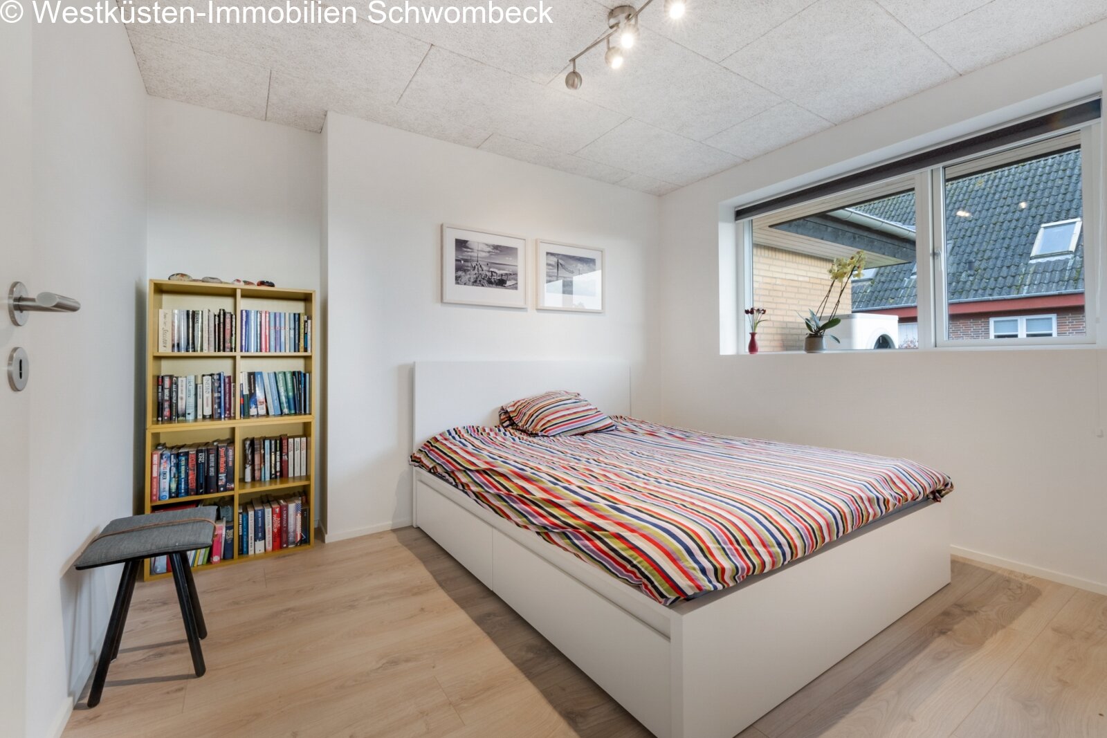 Helles Schlafzimmer mit großflächigen Fenstern und praktischen Einbauregalien