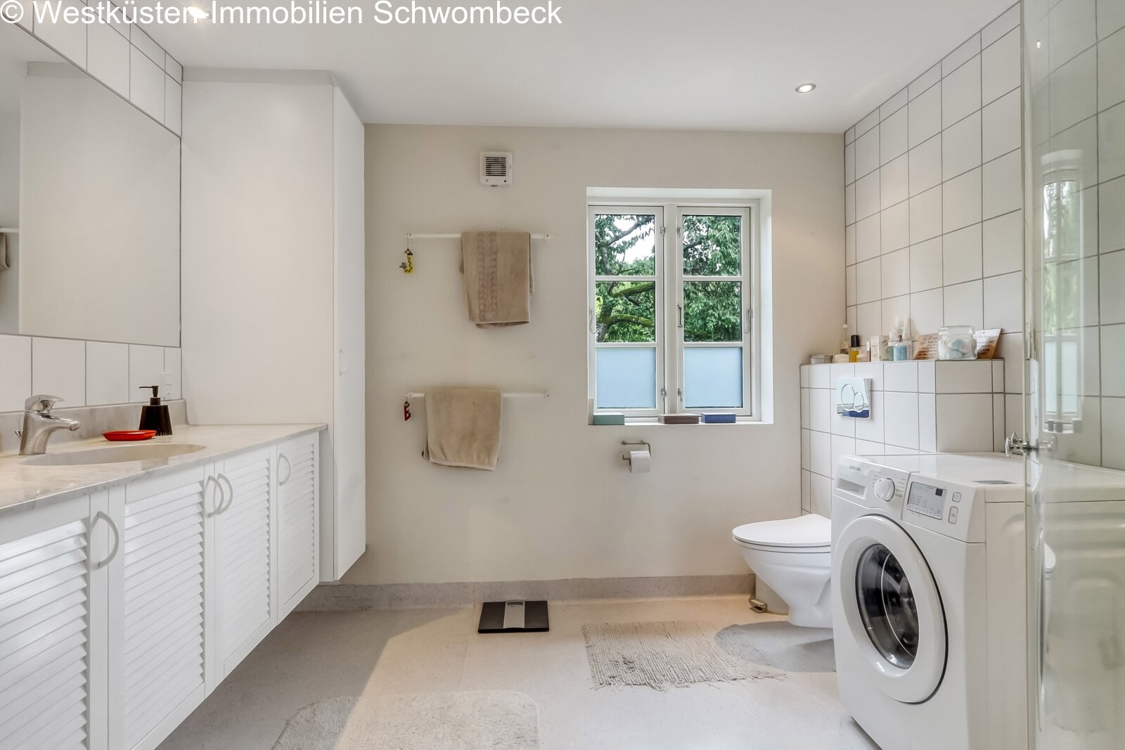 Modernes Badezimmer mit integrierter Waschmaschine und Fensterblick Modernes Badezimmer mit integrierter Waschmaschine und Fensterblick