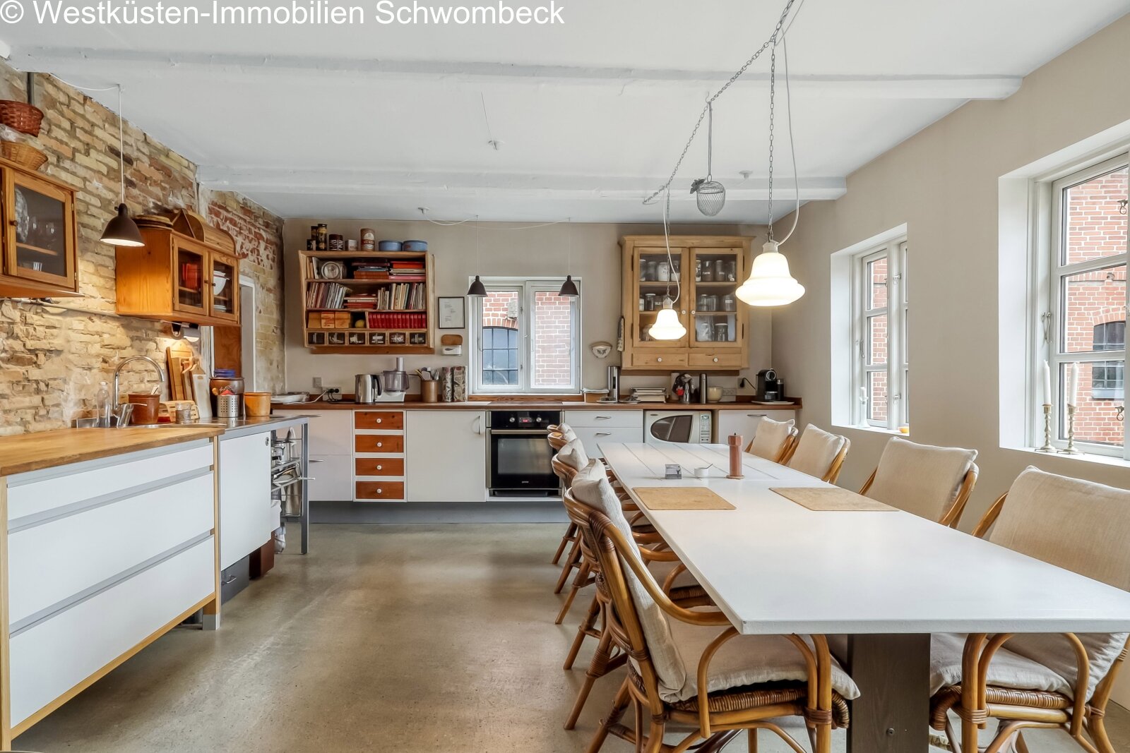 Offene Wohnküche mit Steinwand und großflächigen Fenstern Offene Wohnküche mit Steinwand und großflächigen Fenstern
